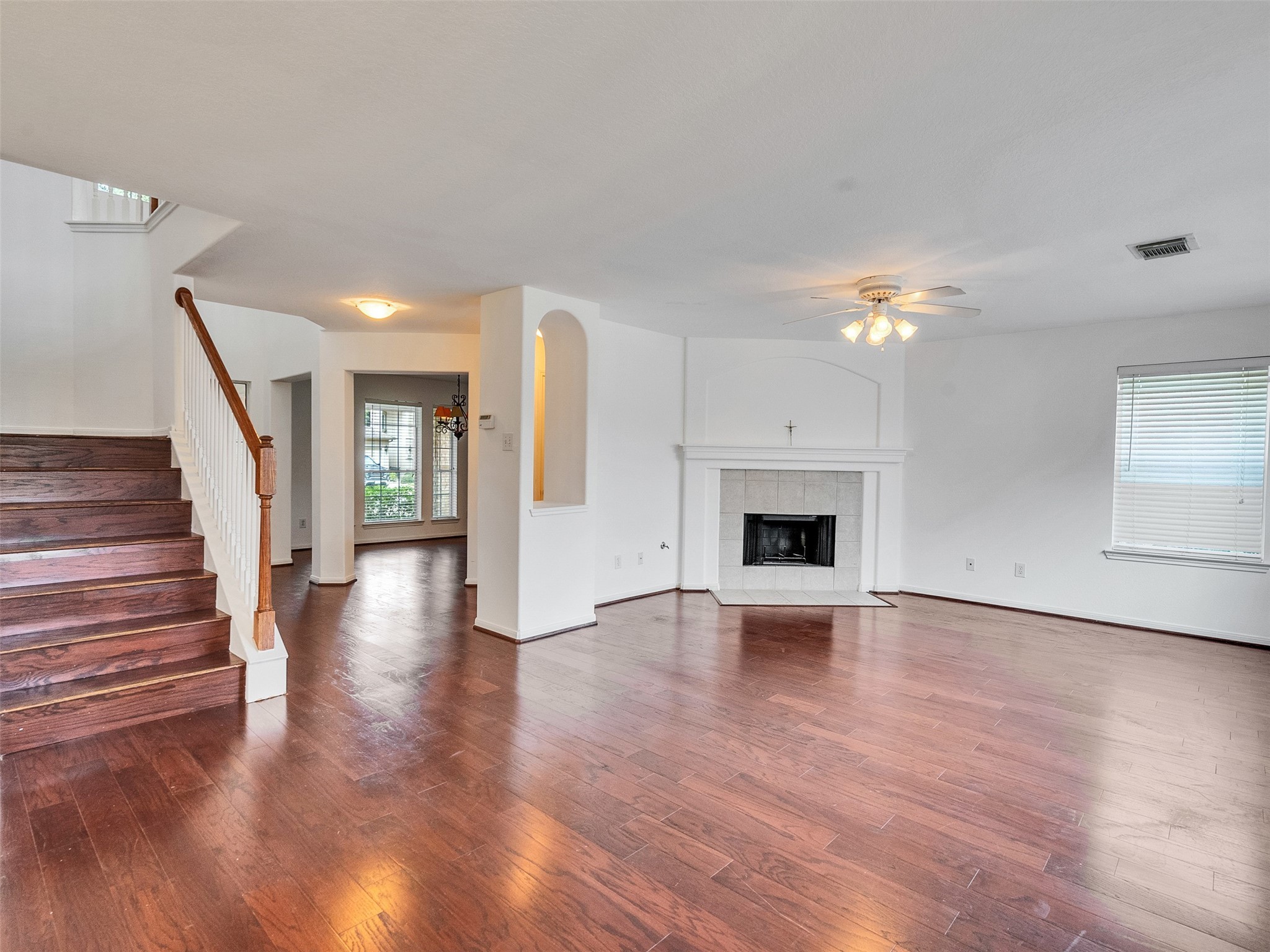 3307 Manor Tree Lane Houston, TX 77068 - Photo 10 of 44 This spacious living area features rich hardwood floors, a cozy fireplace, and abundant natural light. It includes an elegant staircase leading upstairs and an adjacent dining area with large windows and a stylish chandelier. Ideal for comfortable living and entertaining.