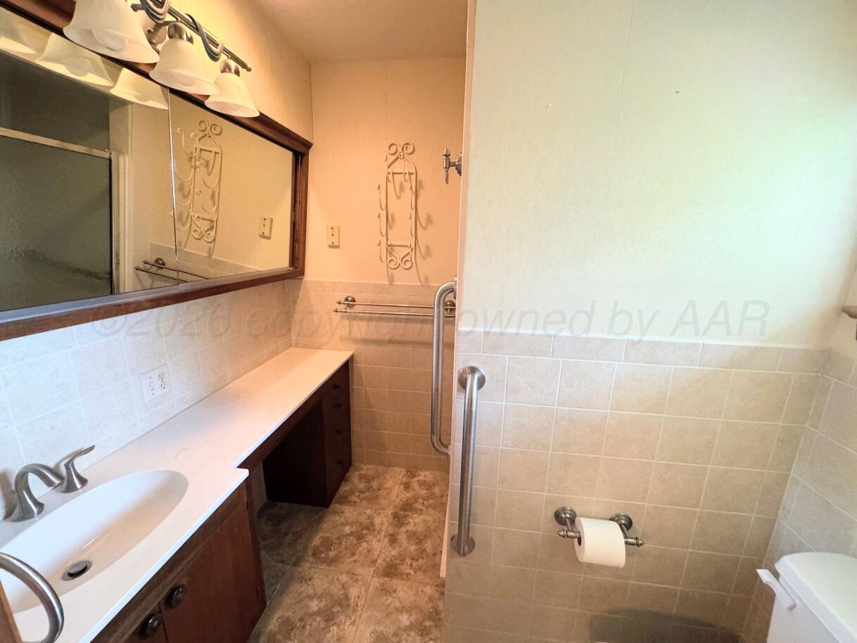 1709 South Eton Street Perryton, TX 79070 - Photo 14 of 22 a bathroom with a sink and a mirror