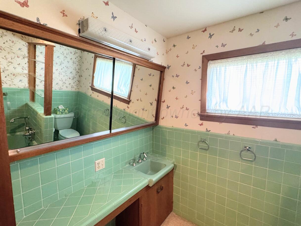 1709 South Eton Street Perryton, TX 79070 - Photo 8 of 22 a bathroom with a granite countertop sink and a large mirror