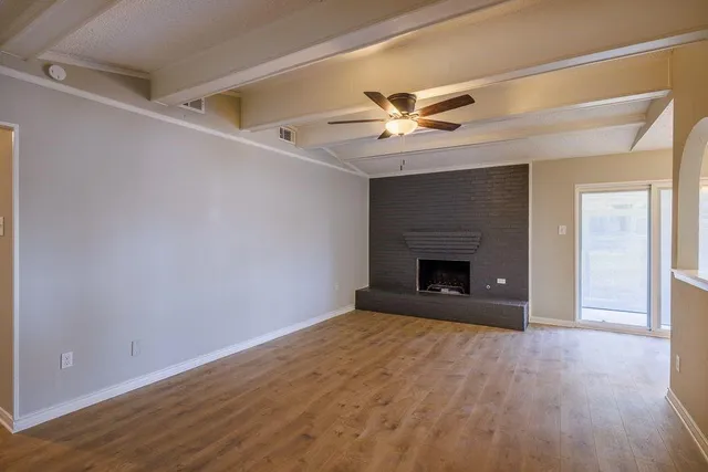an empty room with wooden floor fireplace and windows