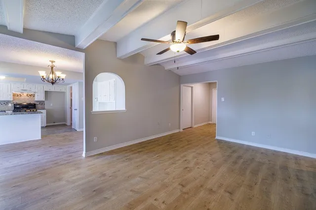 a view of an empty room with a chandelier fan