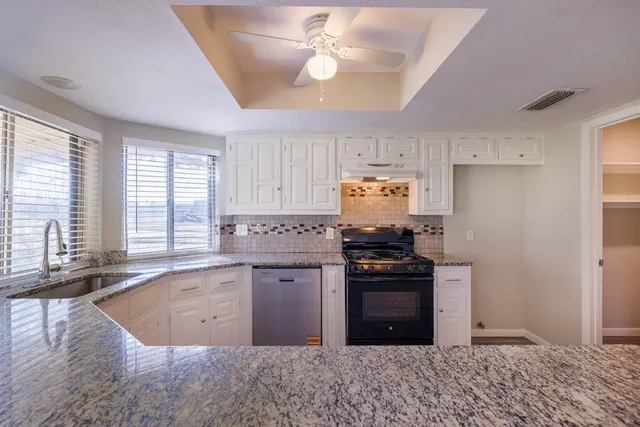 a large kitchen with granite countertop a stove and a sink