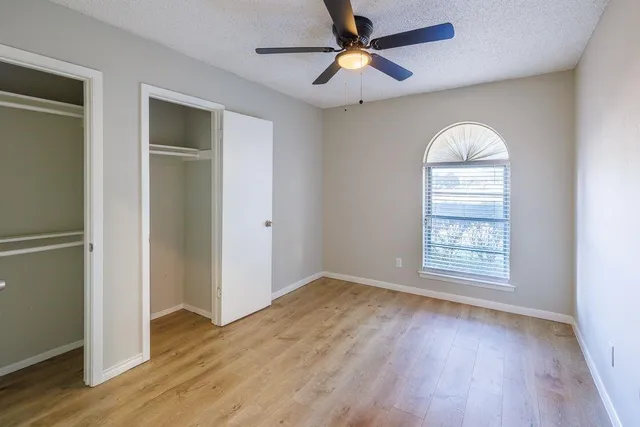 an empty room with chandelier fan and windows