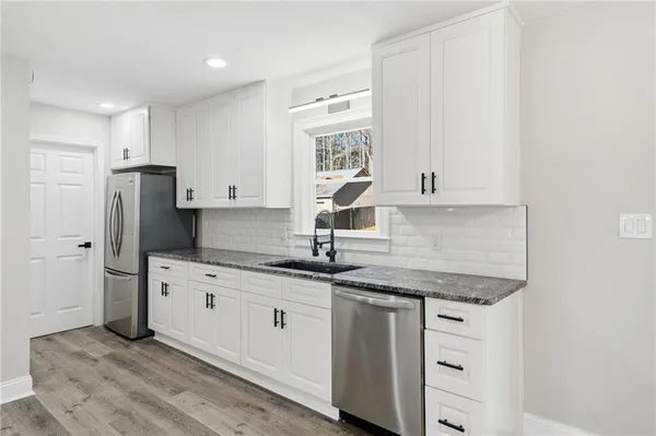 a kitchen with granite countertop white cabinets and stainless steel appliances