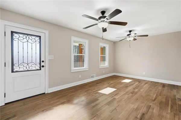 a view of an empty room with a window and wooden floor