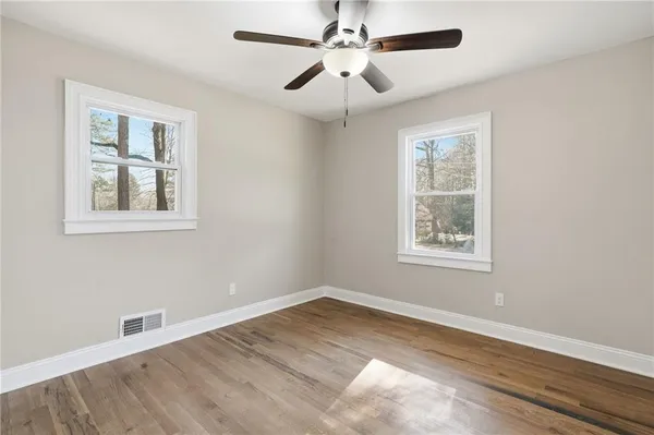 an empty room with wooden floor and ceiling fan