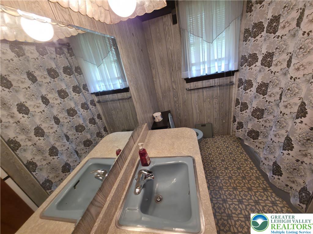 50 Montovision Road Mount Pocono, PA 18344 - Photo 16 of 32 This bathroom features a double vanity and patterned flooring, offering functional utility.
