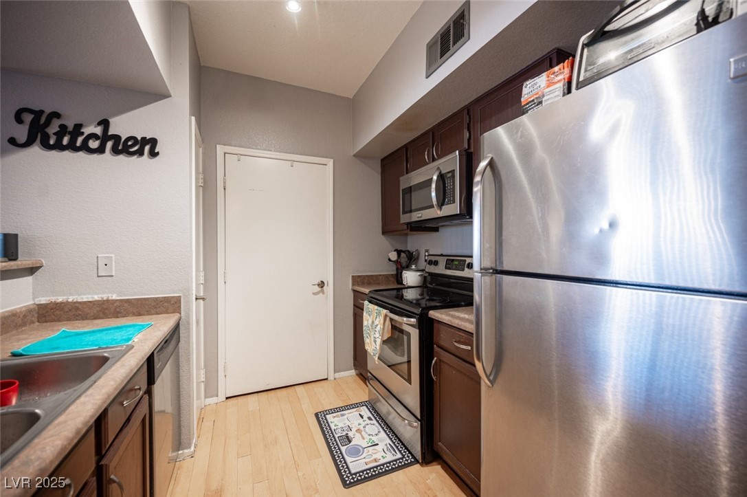 6650 West Warm Springs Road, Unit 1079 Las Vegas, NV 89118 - Photo 14 of 37 Kitchen with dark brown cabinets, light wood-style floors, visible vents, stainless steel appliances, and a sink