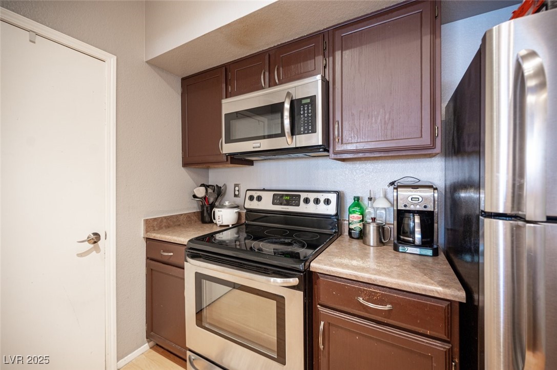 6650 West Warm Springs Road, Unit 1079 Las Vegas, NV 89118 - Photo 16 of 37 Kitchen with dark brown cabinets, light countertops, baseboards, and stainless steel appliances