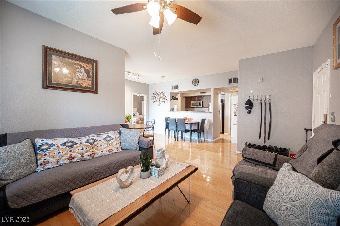 6650 West Warm Springs Road, Unit 1079 Las Vegas, NV 89118 - Photo 6 of 37 Living area featuring light wood-type flooring, rail lighting, a ceiling fan, and visible vents