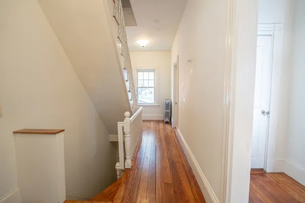 a view of a hallway with wooden floor and staircase