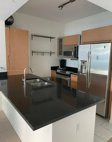 a kitchen with stainless steel appliances granite countertop a sink and a refrigerator