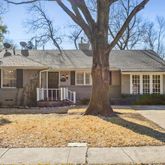 a front view of a house with a yard and large trees