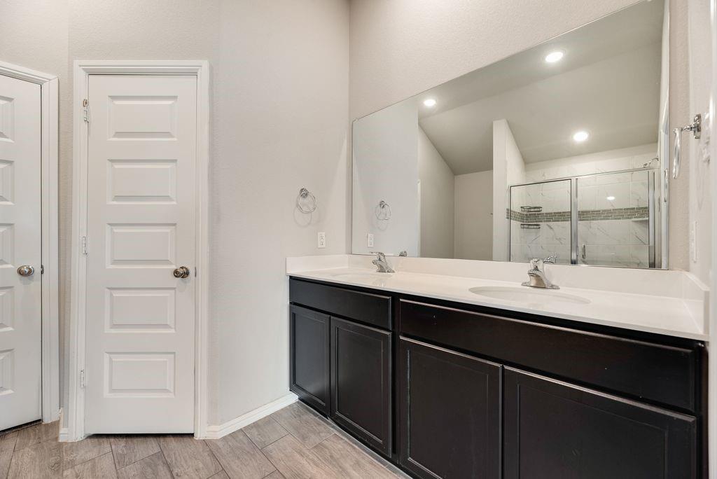 14216 Aberavon Drive Pilot Point, TX 76258 - Photo 13 of 19 Dual vanity with white countertops, dark wood-finish cabinetry, and wood-finish flooring
