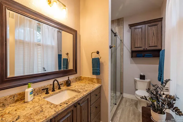a bathroom with a granite countertop sink a mirror and a shower