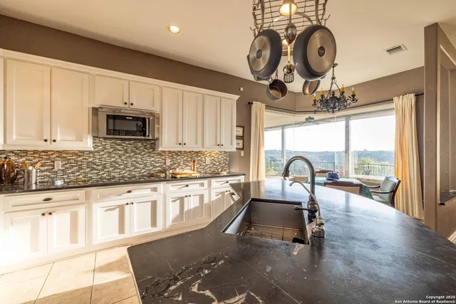 a kitchen with granite countertop a stove a sink a dining table and chair with wooden floor