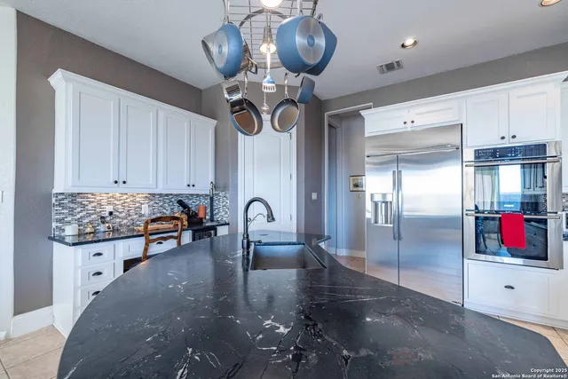 a kitchen with stainless steel appliances kitchen island granite countertop a refrigerator a stove and a sink with wooden floor