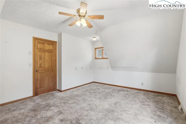 an empty room with a chandelier fan and windows