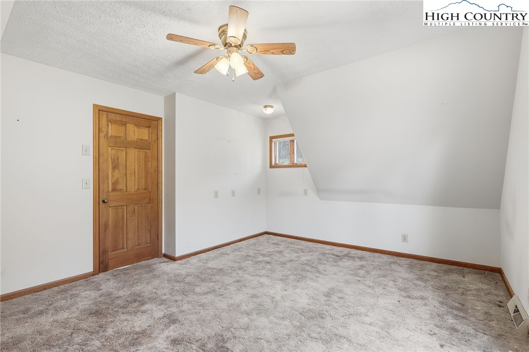 206 Lane L Massey Road Crumpler, NC 28617 - Photo 28 of 36 an empty room with a chandelier fan and windows