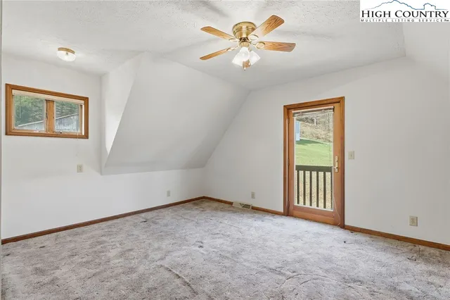an empty room with a chandelier fan and windows