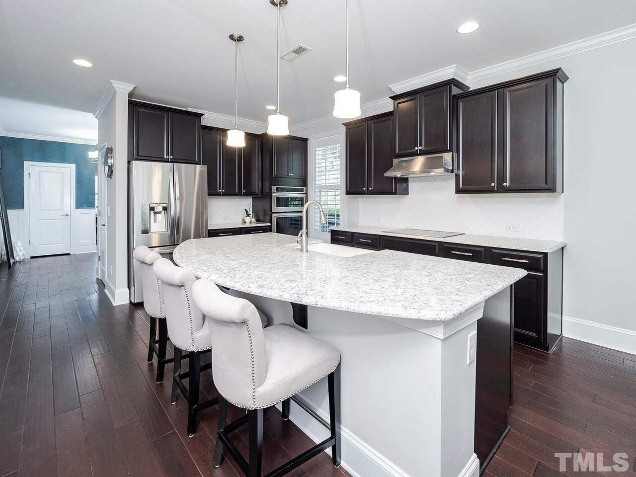 3936 Ivory Rose Lane Raleigh, NC 27612 - Photo 4 of 12 a kitchen with stainless steel appliances kitchen island granite countertop a kitchen island hardwood floor sink and stove