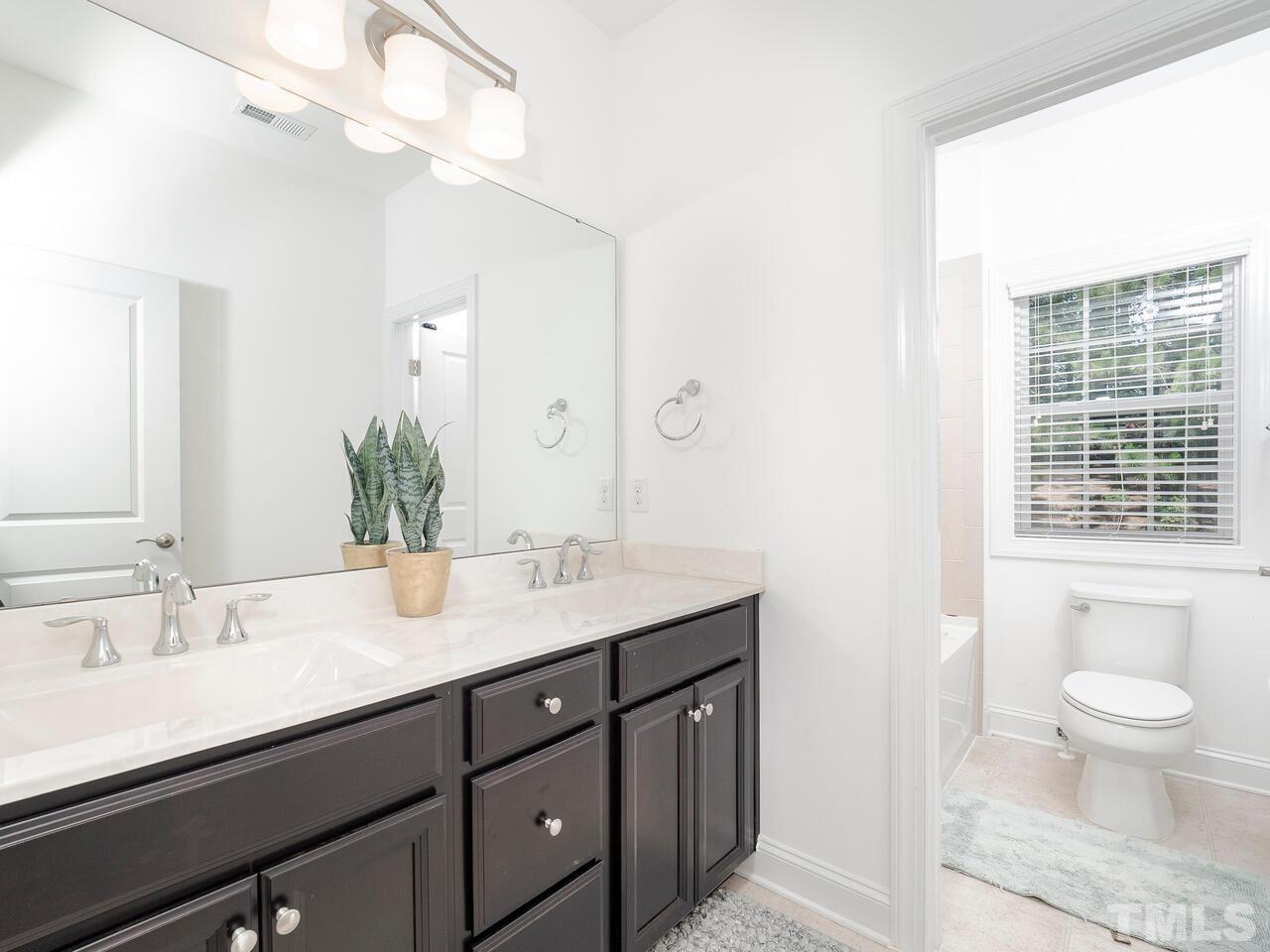 3936 Ivory Rose Lane Raleigh, NC 27612 - Photo 6 of 12 a spacious bathroom with a granite countertop sink a toilet and a mirror