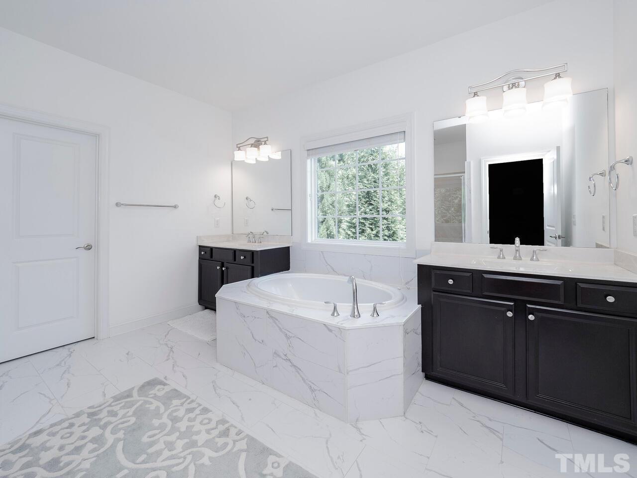 3936 Ivory Rose Lane Raleigh, NC 27612 - Photo 9 of 12 a spacious bathroom with a tub sink and mirror