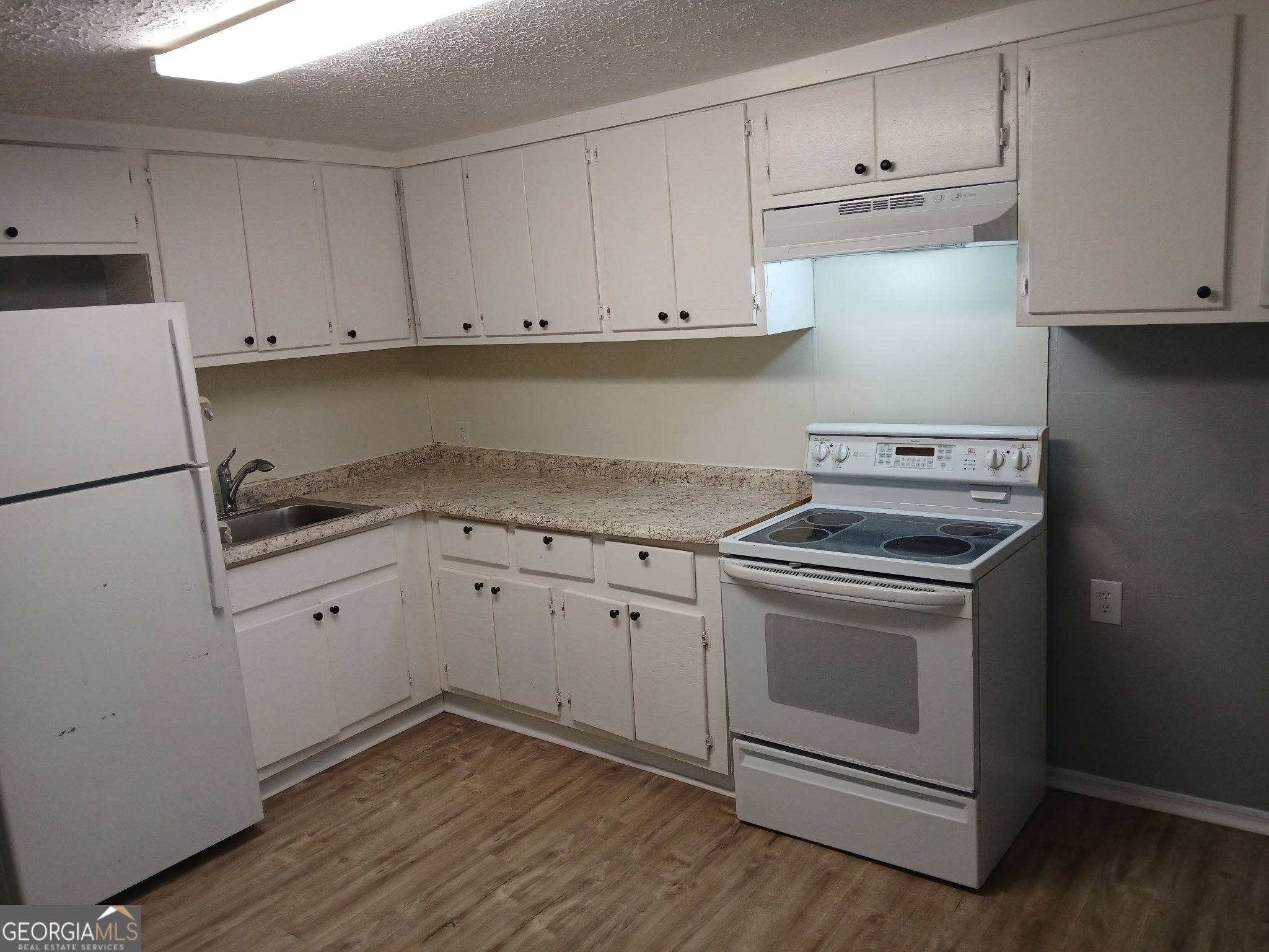 a kitchen with granite countertop white cabinets and white appliances