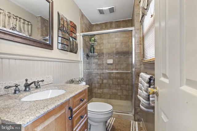 a bathroom with a granite countertop sink toilet and shower