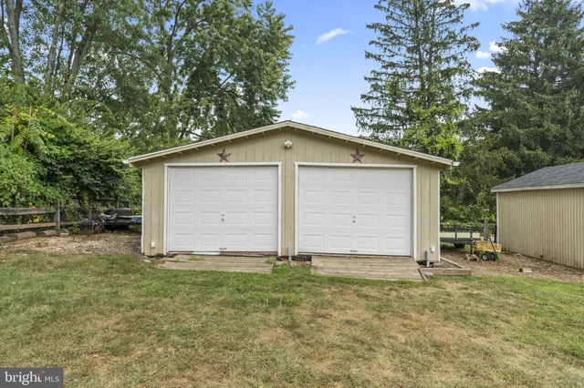 a tall yellow house with a yard and trees in the background