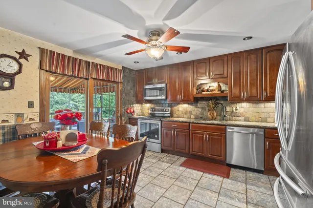 a kitchen with stainless steel appliances granite countertop a stove a refrigerator a sink dishwasher a dining table and chairs with wooden floor