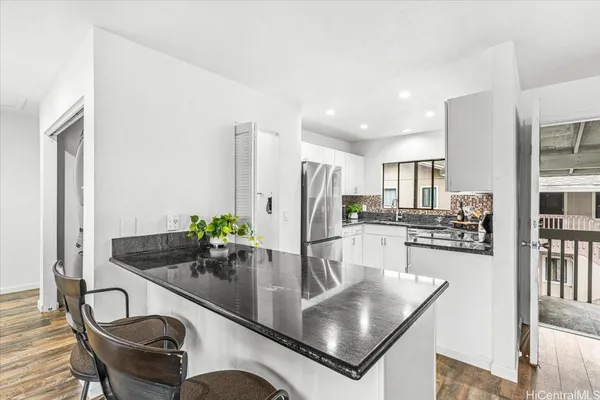 a kitchen with stainless steel appliances granite countertop a dining table chairs and refrigerator