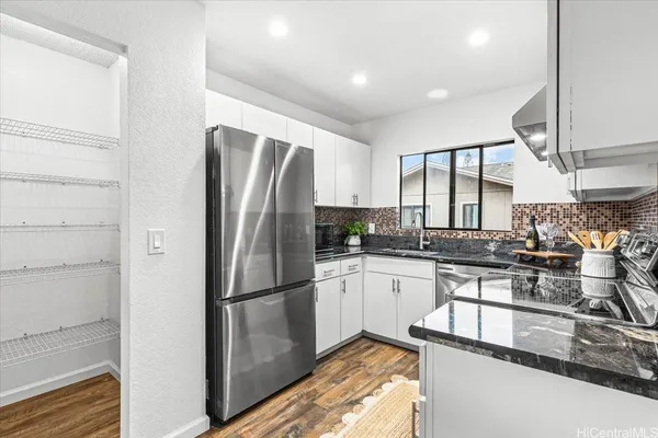 a kitchen with stainless steel appliances granite countertop a refrigerator a stove and a sink with wooden floor