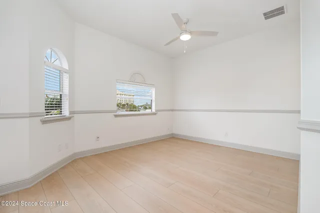 an empty room with windows and fan
