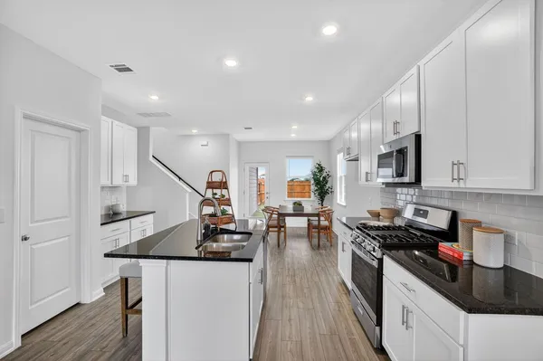 a kitchen with granite countertop a sink a counter top space stainless steel appliances and wooden floor