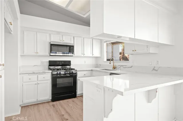 a kitchen with a sink white cabinets and stainless steel appliances