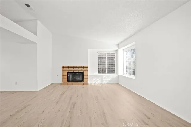 a view of an empty room with a window and fireplace