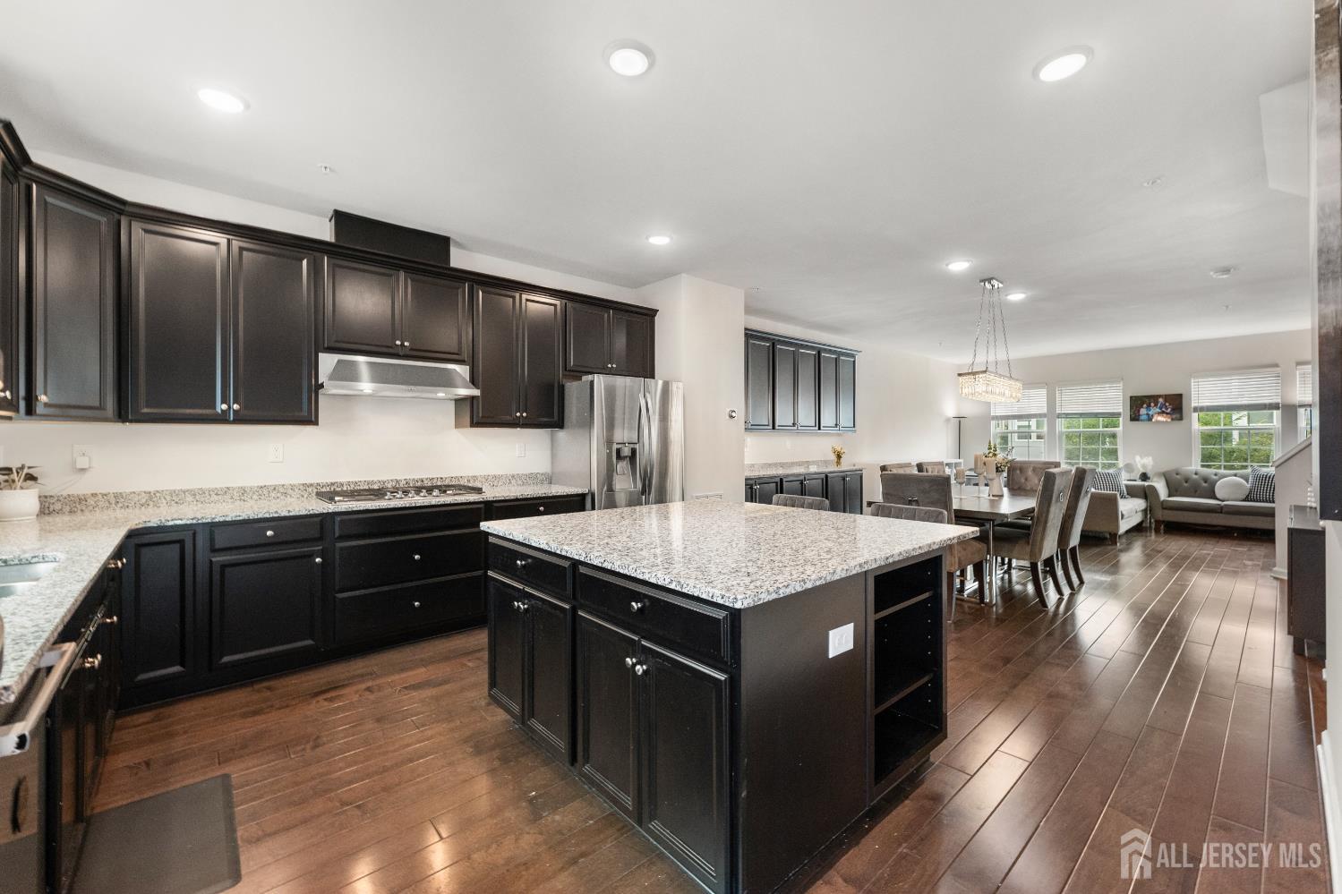 a kitchen with stainless steel appliances granite countertop wooden cabinets a sink dishwasher a stove and a refrigerator with wooden floor