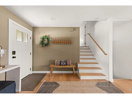 a living room with a bed and a black kitchen with white walls