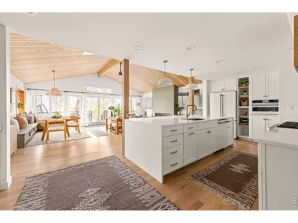 a kitchen with stainless steel appliances kitchen island granite countertop a refrigerator a stove and white cabinets with wooden floor