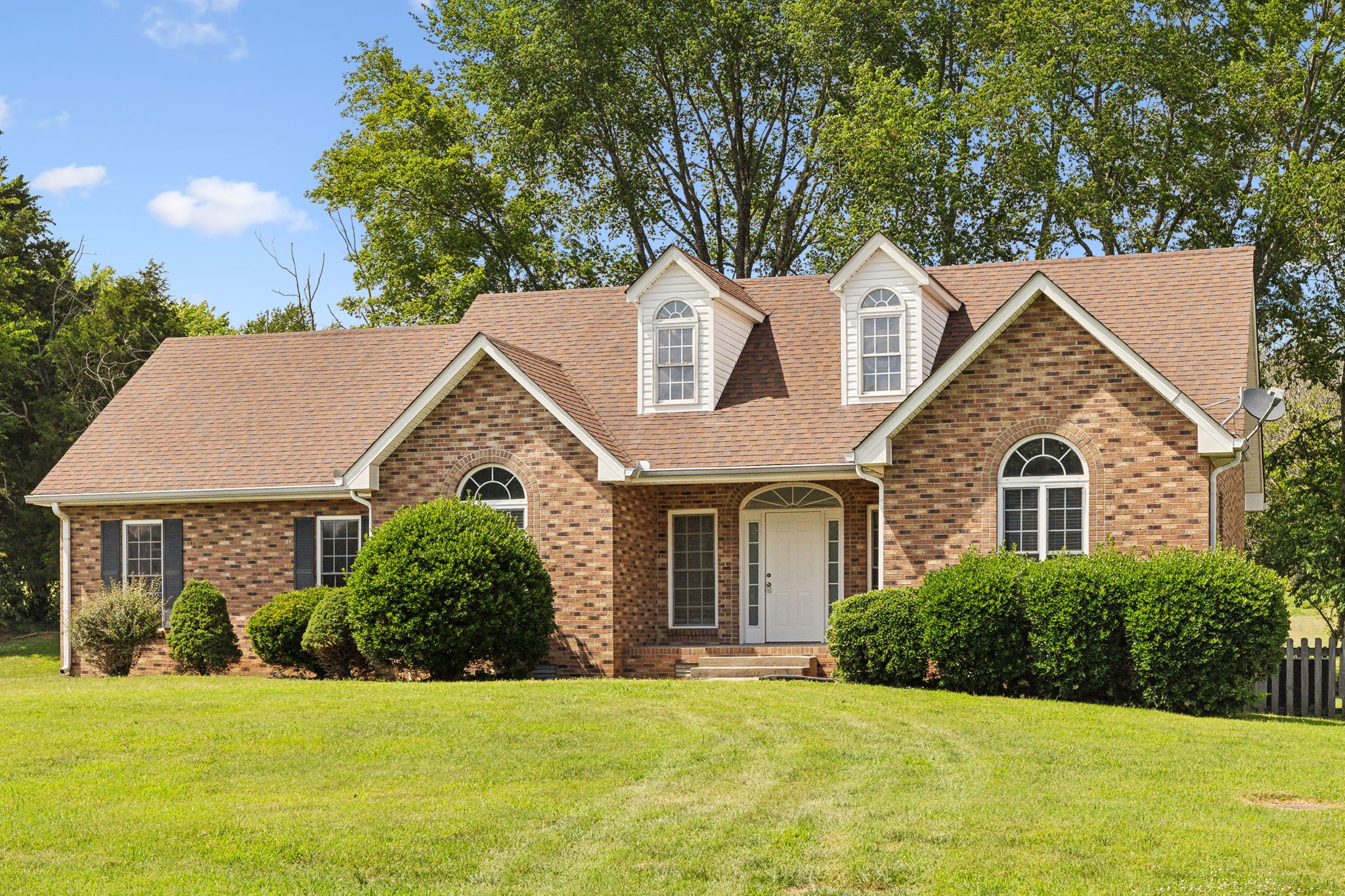 a front view of a house with a yard and trees