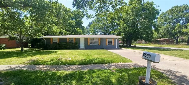 a front view of a house with a yard and trees