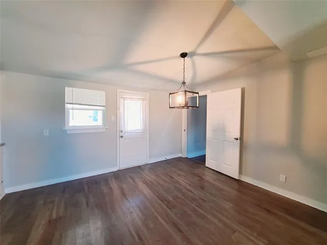 an empty room with wooden floor closet and windows