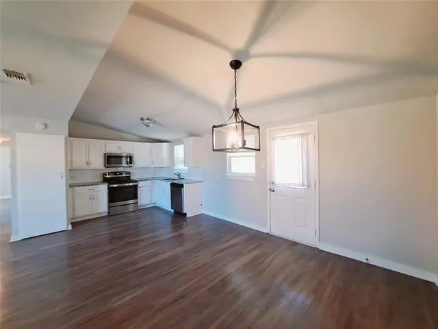 a view of a kitchen with a sink wooden floor a refrigerator and window
