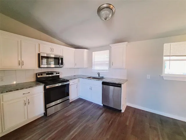 a kitchen with sink a microwave and cabinets