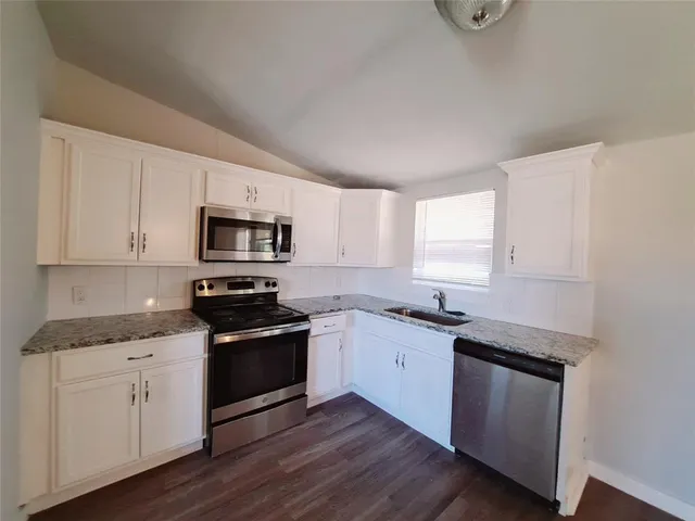 a kitchen with granite countertop white cabinets and appliances