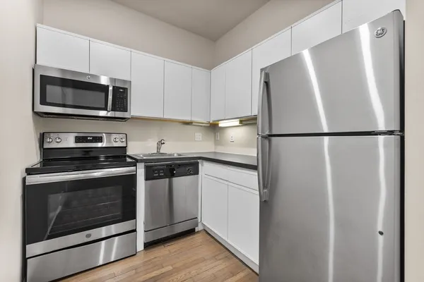 a white refrigerator freezer and a stove sitting inside of a kitchen with granite countertop stainless steel appliances