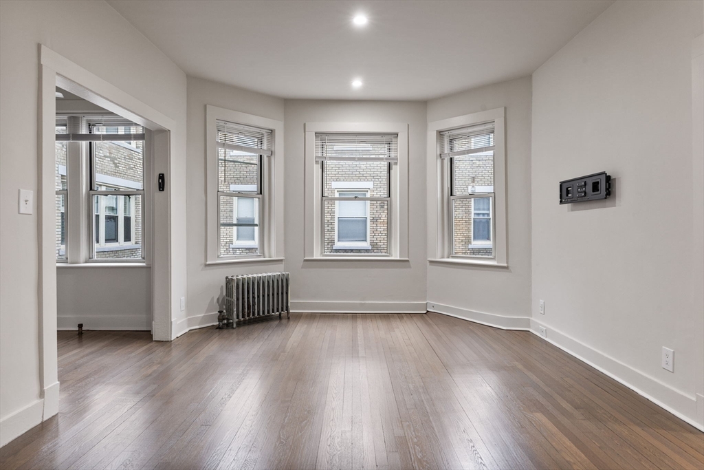 74 Fenway, Unit 45 Boston, MA 02115 - Photo 4 of 12 an empty room with wooden floor and windows
