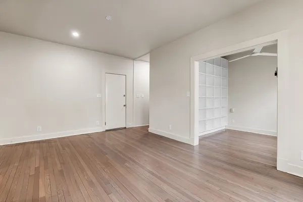 a view of an empty room with wooden floor and closet