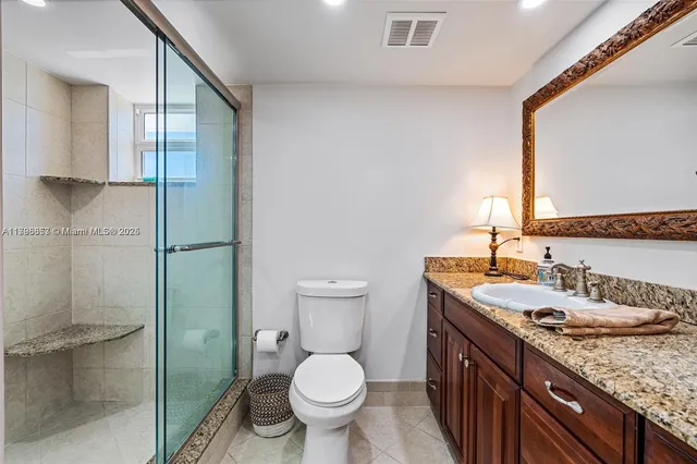 a bathroom with a granite countertop sink toilet and shower